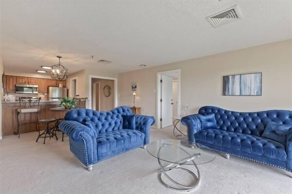 Living room with a couch and love seat.  TV on cabinet has Roku and Direct TV.