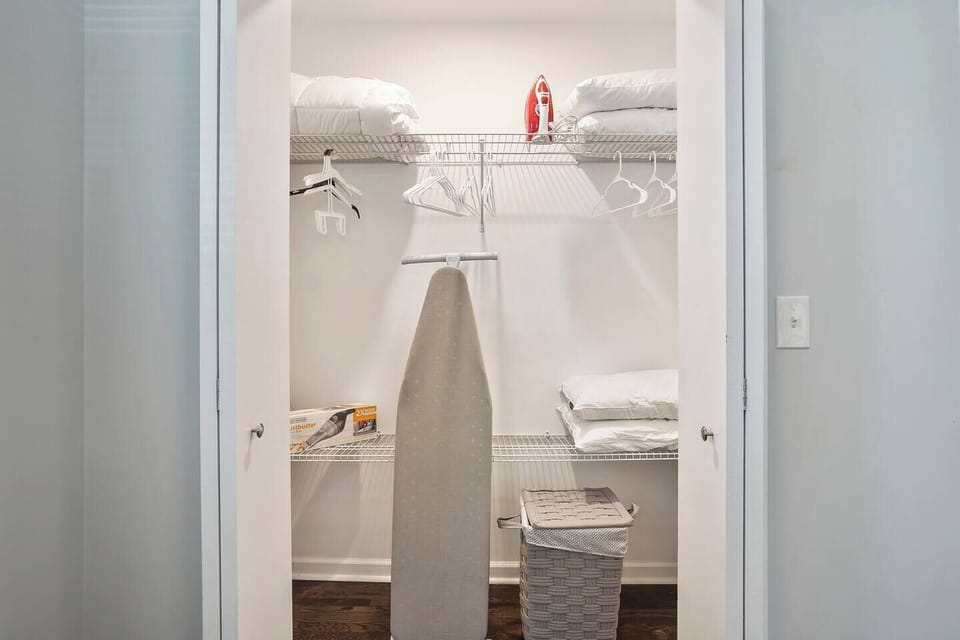 Large master closet, with an iron, ironing board, extra pillows, sheets, and a small hand vac.