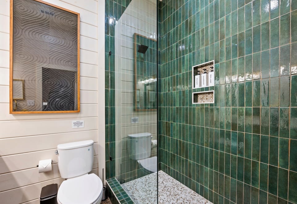Rich green tile and a spacious walk in shower give this bathroom a unique look while providing all the comforts you need.