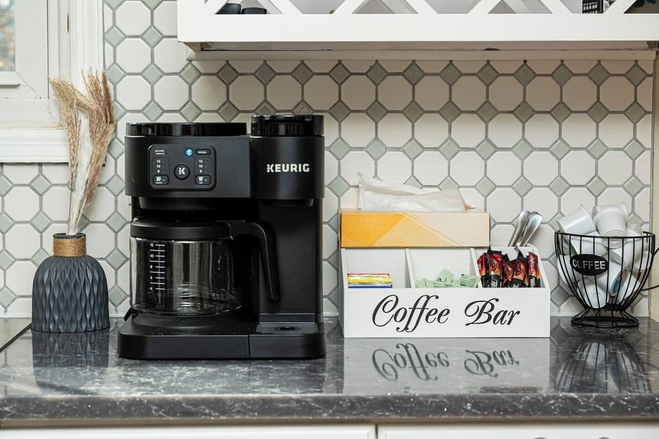 A well-stocked coffee bar with a Keurig coffee maker, a drip coffee maker, and a variety of coffee pods and ground coffee. The coffee bar is organized and inviting, perfect for starting your day with a cup of your favorite brew.