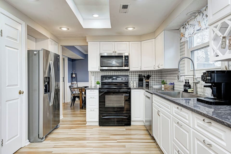 A modern kitchen with sleek appliances, ample counter space, and views of the dining room, the backyard lake and the primary living room.