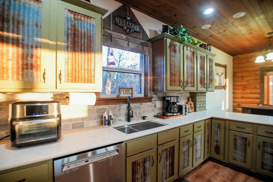 Rustic meets modern in this inviting kitchen, featuring weathered wood cabinets, ample counter space, and all the essentials you need for a comfortable and enjoyable stay.