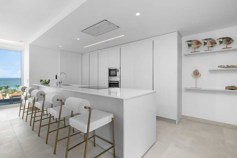 A sleek, modern kitchen awaits with pristine countertops and an inviting island where you can gather for meals with stunning ocean views framing your stay.