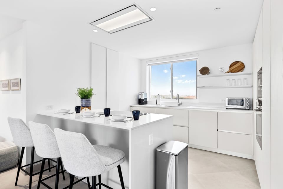 Enjoy your morning coffee in this bright, modern kitchen with sleek countertops, stylish bar seating, and everything you need to prepare your favorite meals.
