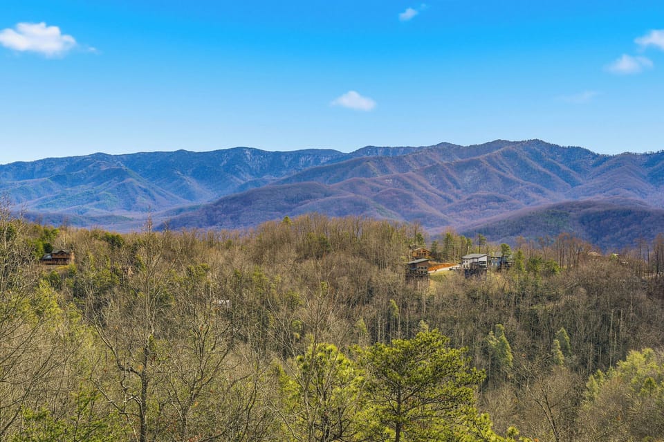 Stunning mountain vistas stretch across layered ridges beneath bright blue skies, showcasing the natural beauty surrounding this peaceful retreat.