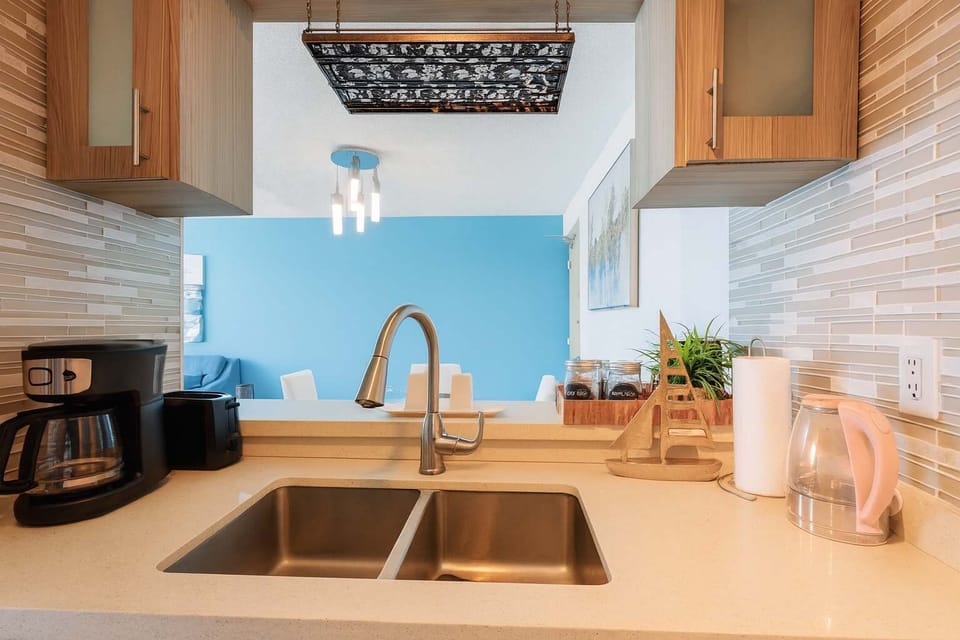Bright and modern kitchen view overlooking the living area. Clean countertops, stylish backsplash, and open layout create a fresh, inviting feel for your island getaway.
