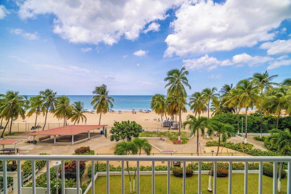 Wake up to swaying palms, golden sands, and endless ocean blues from your private beachfront balcony in Isla Verde.