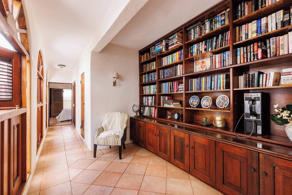 Inviting hallway library with rich wooden shelves, warm lighting, and vintage charm — a perfect reading nook that captures the elegance of Old San Juan.