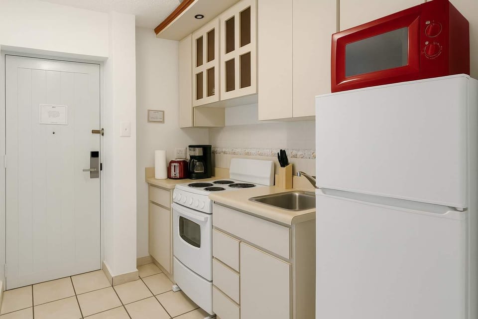 Cozy and well-equipped kitchenette featuring ample cabinet storage, a full-size fridge, stove, microwave, and essential appliances. Perfect for preparing simple meals during your stay.