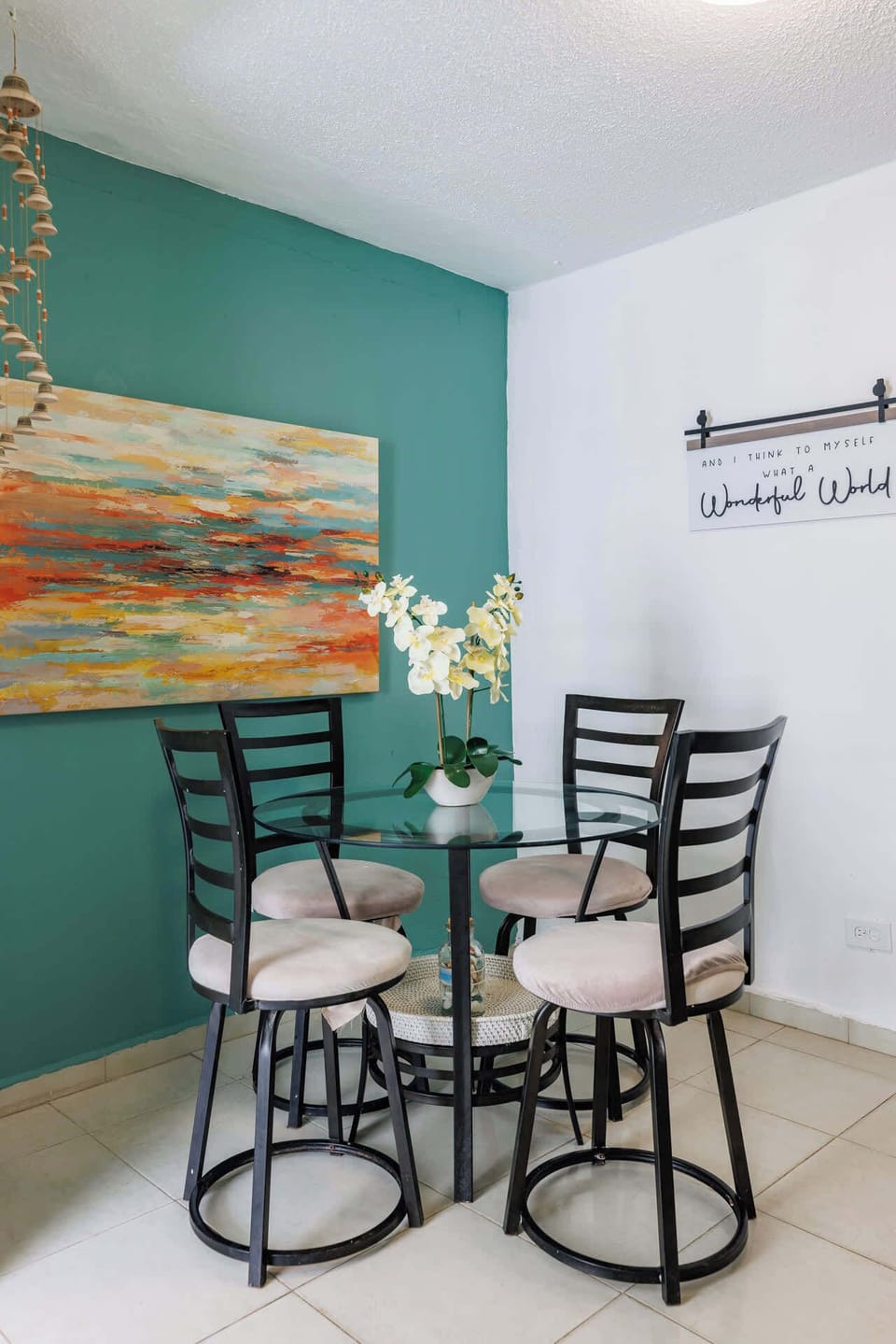 Charming breakfast nook with vibrant artwork and cozy seating for four. The glass table and fresh decor create a bright, welcoming corner — perfect for morning coffee or casual meals.