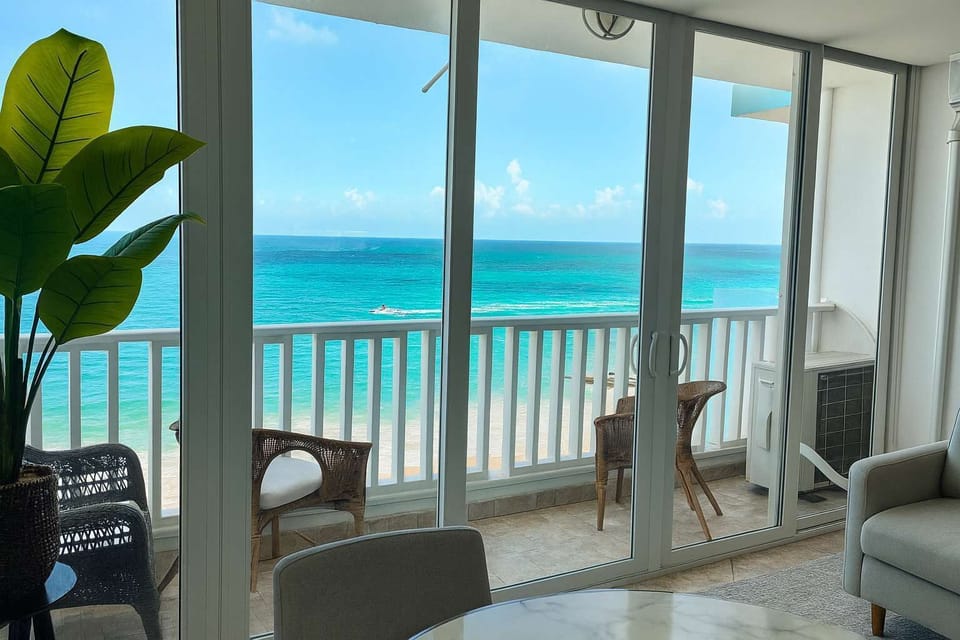 Bright and airy living space with panoramic ocean views — enjoy the turquoise waters from your private balcony right off the living room.
