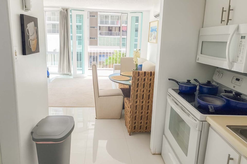 Bright, open-concept kitchen and dining area leading to a sunlit living space with balcony views — perfect for relaxing after a day by the beach.