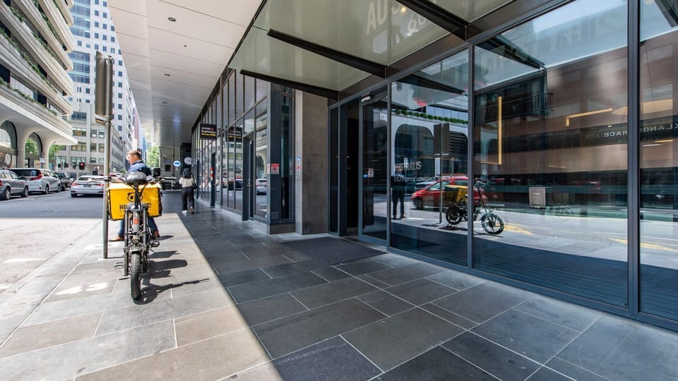 The building’s sleek, contemporary glass facade and wide paved sidewalk offer a premium, sophisticated street presence.