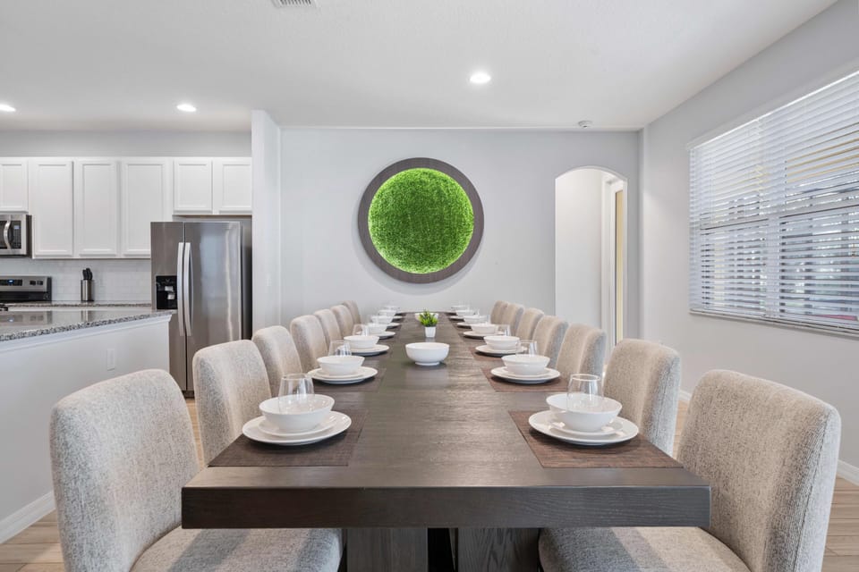 - Long dining table with seating for large family groups  
- Elegant neutral chairs set beside bright green wall art  
- Orlando vacation rental with family dining for events