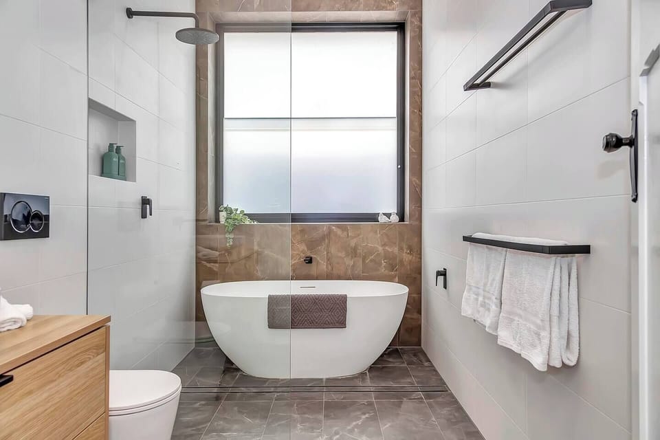 The main bathroom features a luxurious freestanding bath and walk-in shower, perfect for unwinding after a day at the beach.
