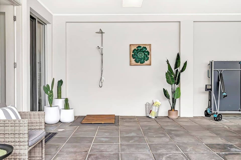 At the rear, an undercover patio features a convenient beachside shower, a BBQ, and a ping pong table—perfect for rinsing off, relaxing, and soaking your cares away.
