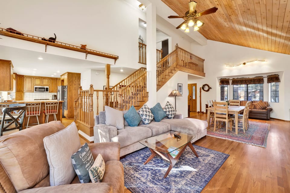 Cozy mountain living room with a stone fireplace, comfy seating, and smart TV—perfect for relaxing evenings, movie nights, and warm cabin vibes after outdoor adventures.