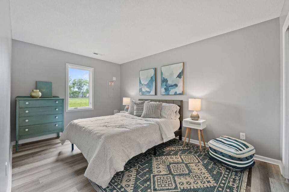 Elegant queen-sized bedroom with a spacious layout and large window, allowing natural light to create a bright and airy atmosphere.