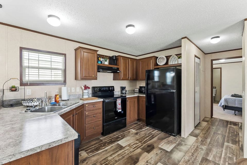 Spacious kitchen with wraparound counters, black appliances, and direct access to nearby bedrooms for added convenience.
