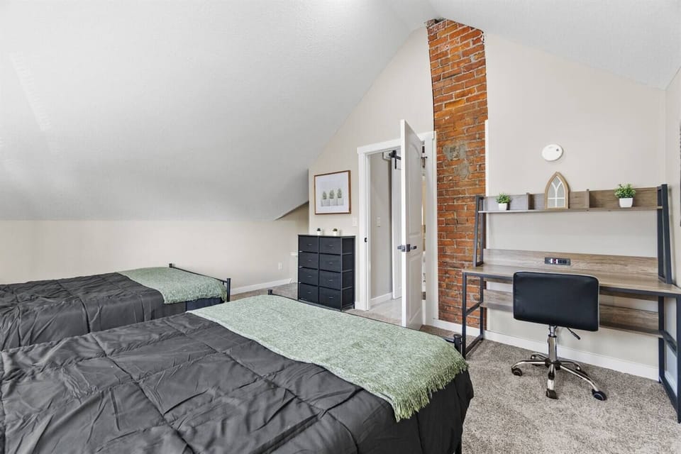 A cozy bedroom with a comfortable bed, along with a desk and office chair, ideal for work or study.
