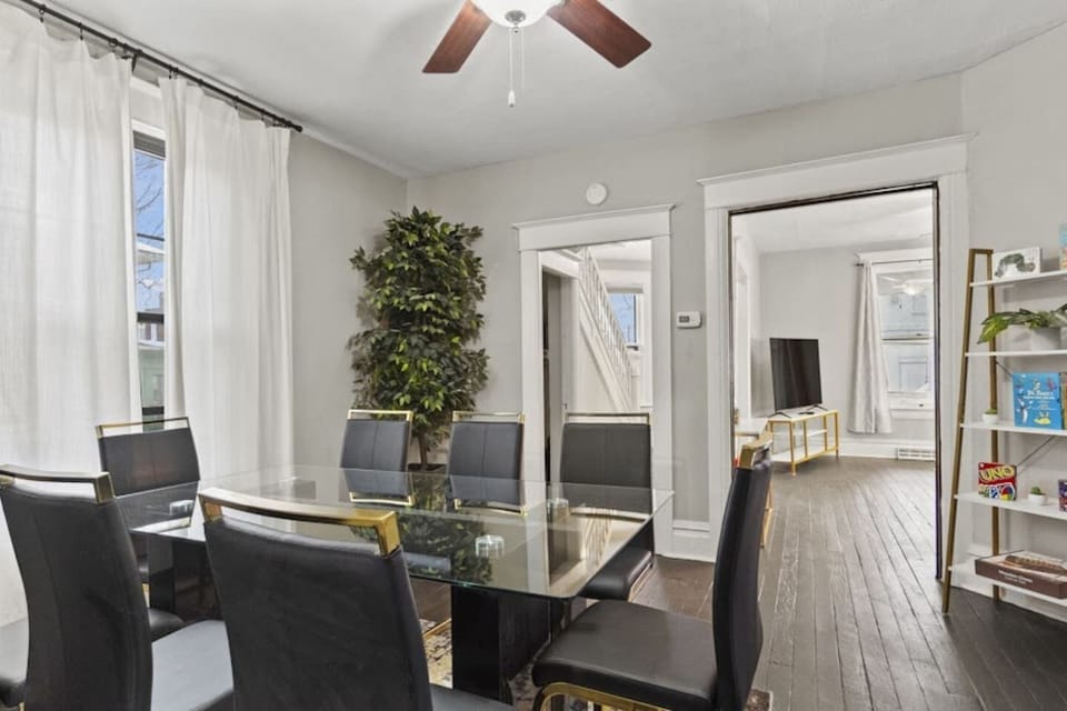 Refined dining area with an elegant table and chairs, stylish decorations, plush curtains, chandelier fan, and a functional divider leading to the living room—creating a seamless blend of sophistication and modern comfort