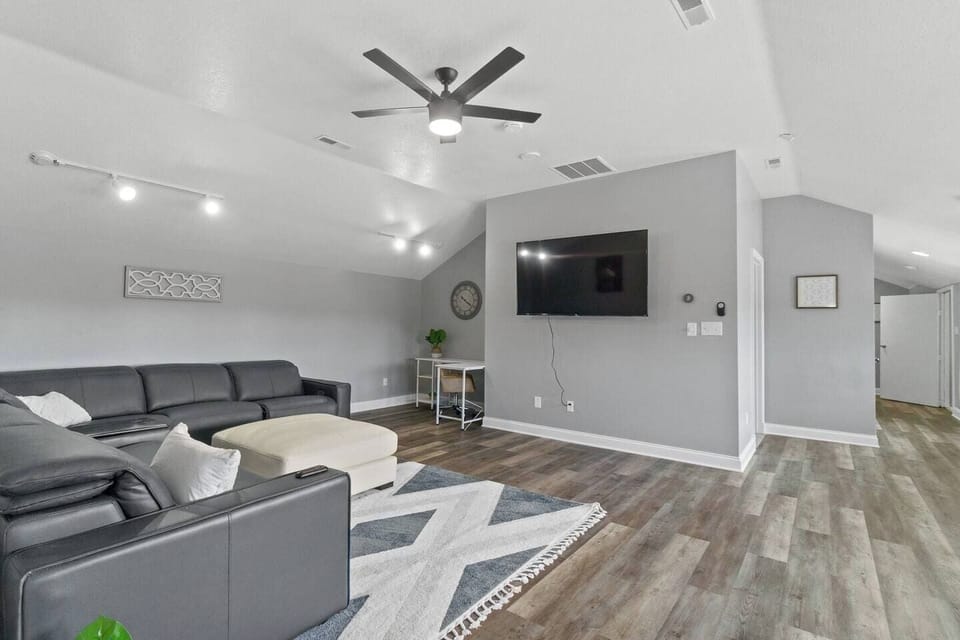 Spacious living area with a plush couch, flat-screen TV, and a soft area rug, creating a perfect space for relaxation and entertainment.