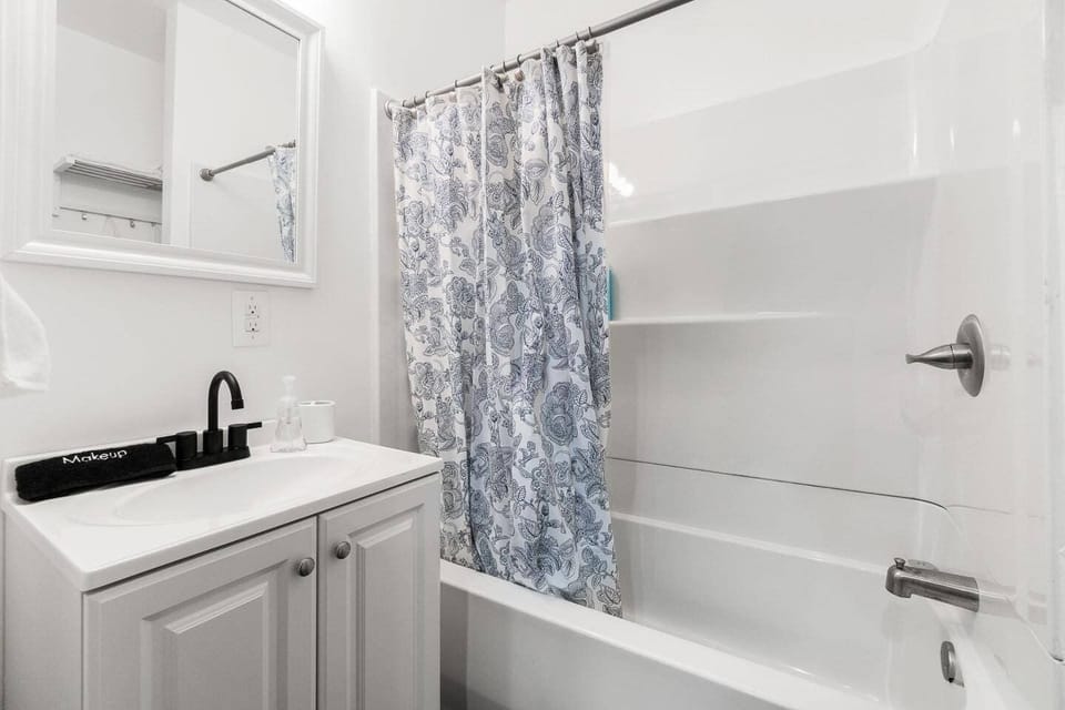 Bright and clean bathroom featuring a relaxing tub, mirror, fresh towels, and essentials like soap, shampoo, and conditioner for your convenience.