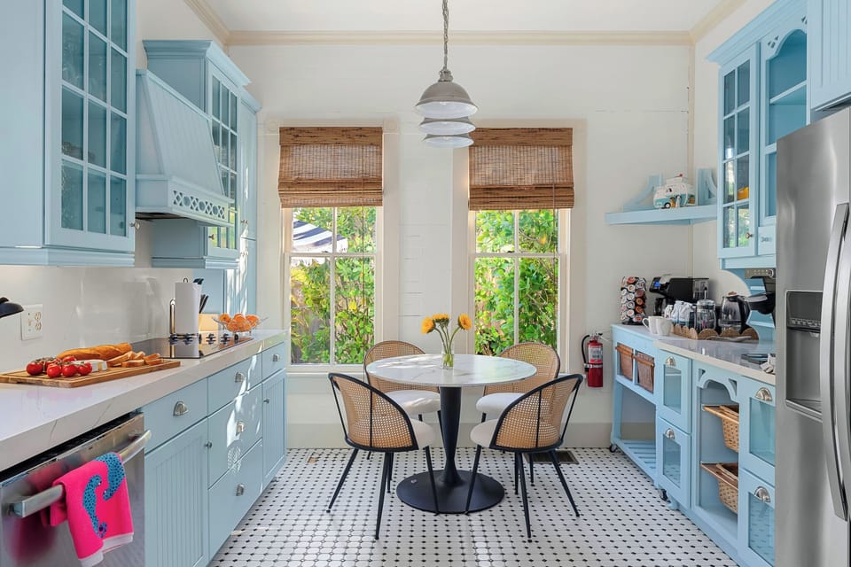 This cheerful kitchen features pastel blue cabinetry, natural wood accents, and a cozy dining nook bathed in sunlight. The perfect blend of style and practicality.