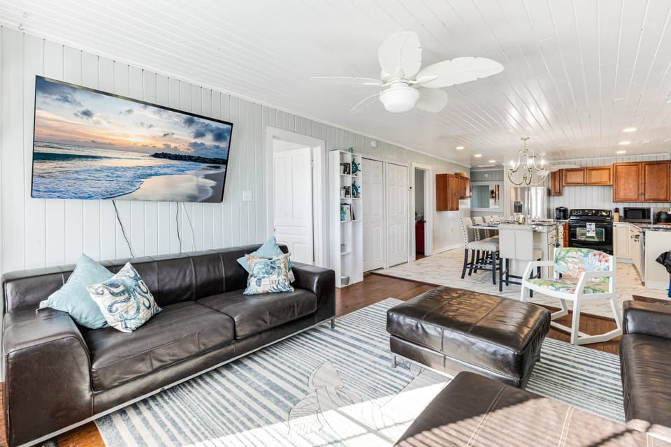 The living area features a comfy sofa, a ceiling fan for added cooling, a flat-screen TV, and a cozy ambiance perfect for relaxation.
