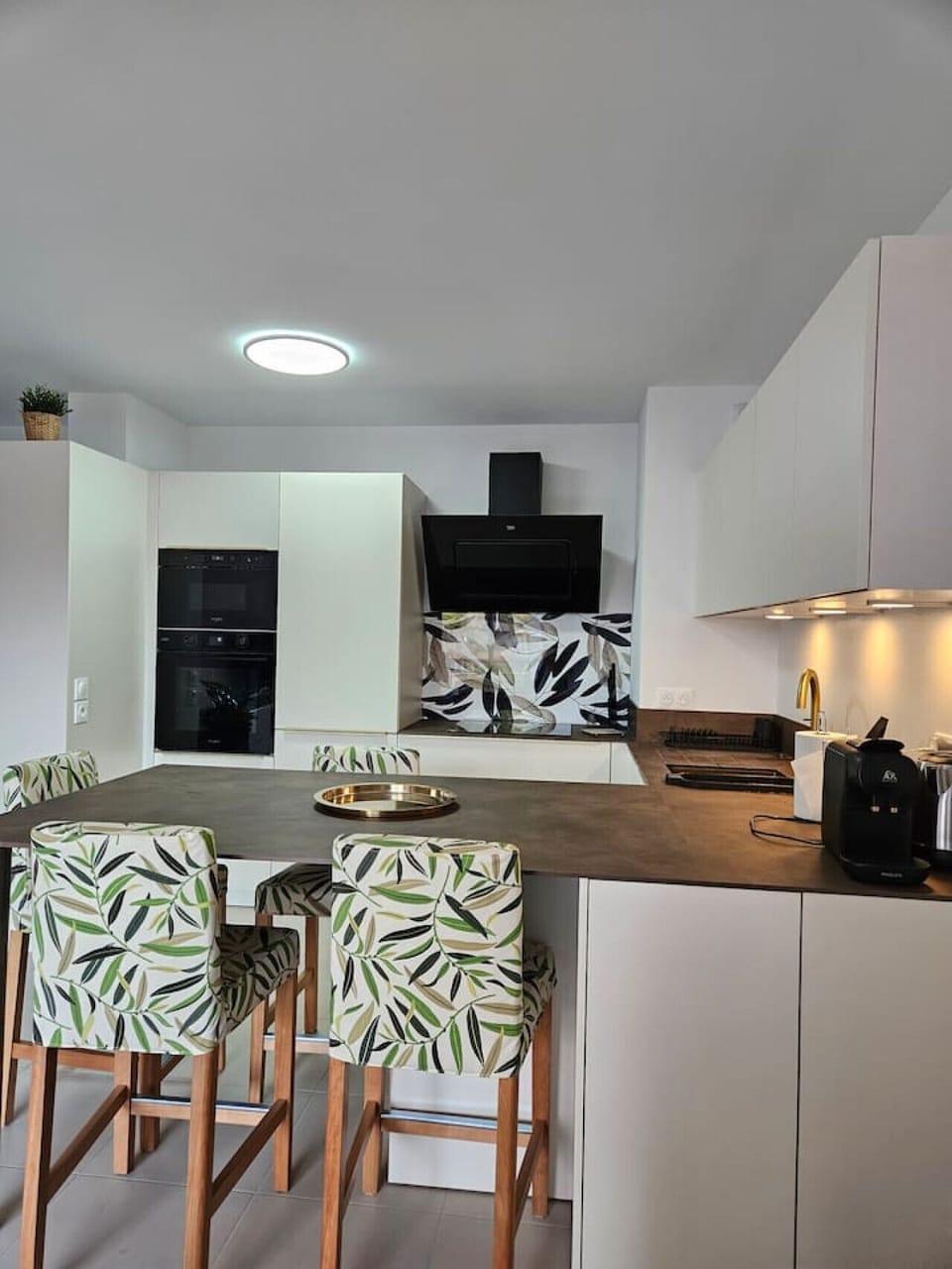 Cette cuisine moderne invite aux plaisirs culinaires. L`îlot central sert de bar pour des moments conviviaux. Imaginez-vous préparer un repas pendant que vos amis se détendent sur les tabourets confortables.