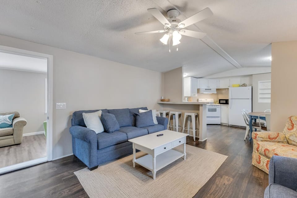 Unwind in your spacious open-concept living area where a comfortable blue sofa invites relaxation beneath the gentle ceiling fan.