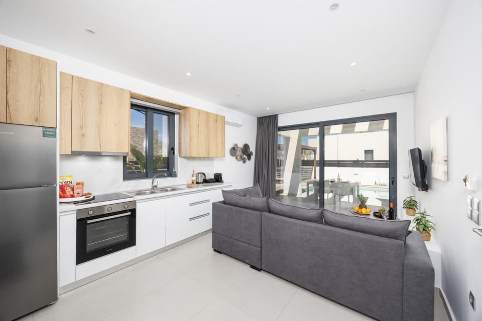 Open-plan living room with sofa, kitchen, A/C, WiFi internet, and satellite TV