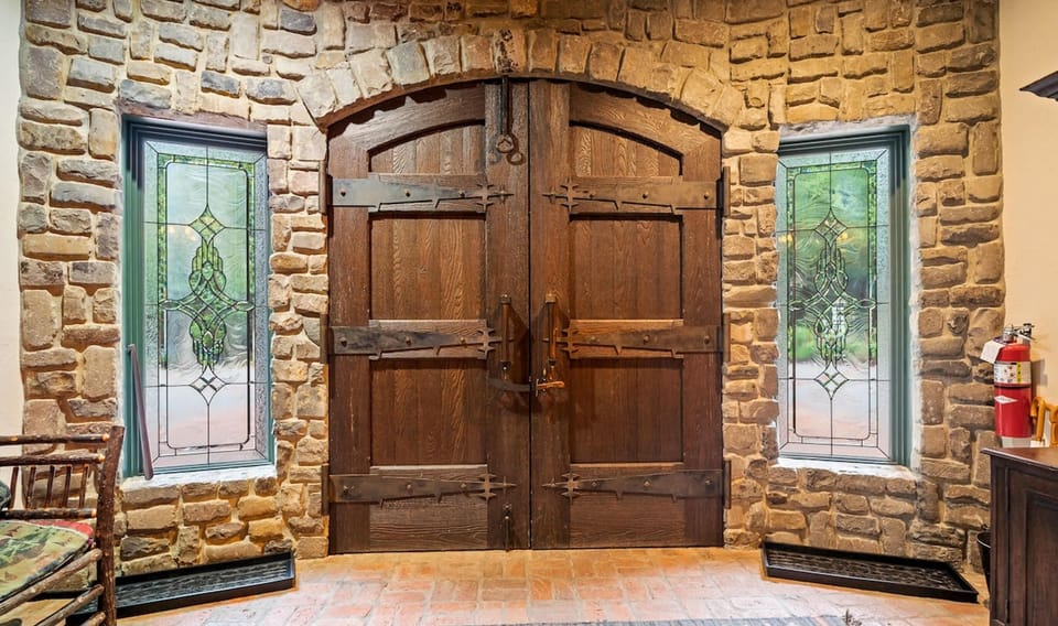 A striking, massive wood front door welcomes you to Scimitar Ridge Ranch, setting the tone for rustic luxury and timeless charm.