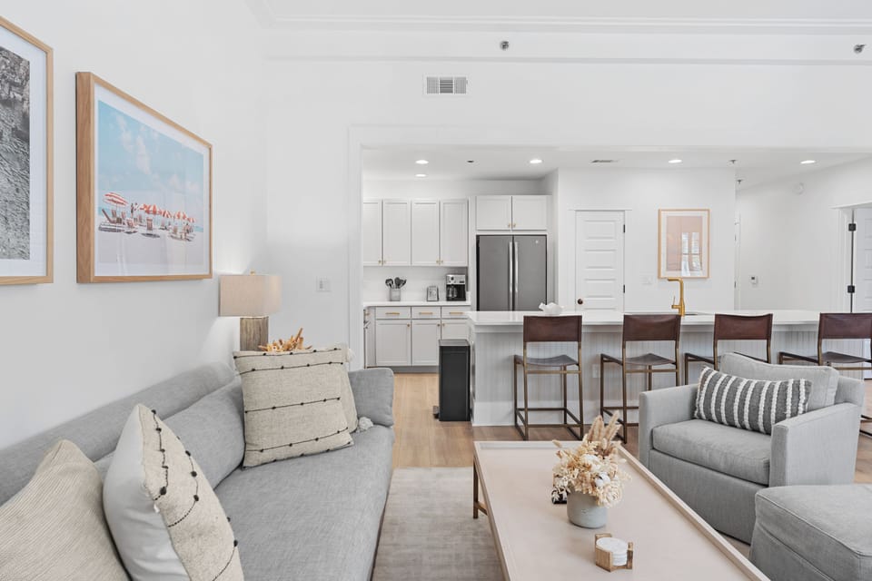 
A contemporary open-plan living room featuring a gray sofa and armchair with decorative pillows.