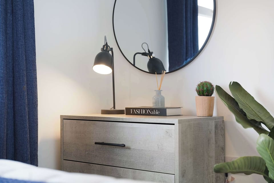 This bright and comfortable bedroom is equipped with a mirror, two bedside tables, a wardrobe space for hanging clothes, and a chest of drawers with a hair dryer. A well-prepared space offering both comfort and practicality during your stay.