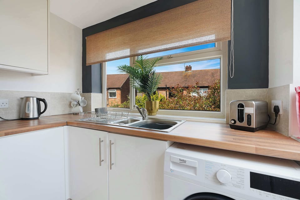 The modern kitchen is fitted with a fridge, freezer, microwave, oven, hob, kettle, toaster, and washing machine. Everyday essentials, including glasses, plates, bowls, cutlery, cooking utensils, and pots and pans, are all ready for use.