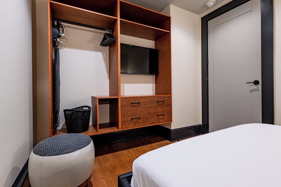 Bedroom 1 - Closet space equipped with hangers, laundry hamper, and iron with ironing board.