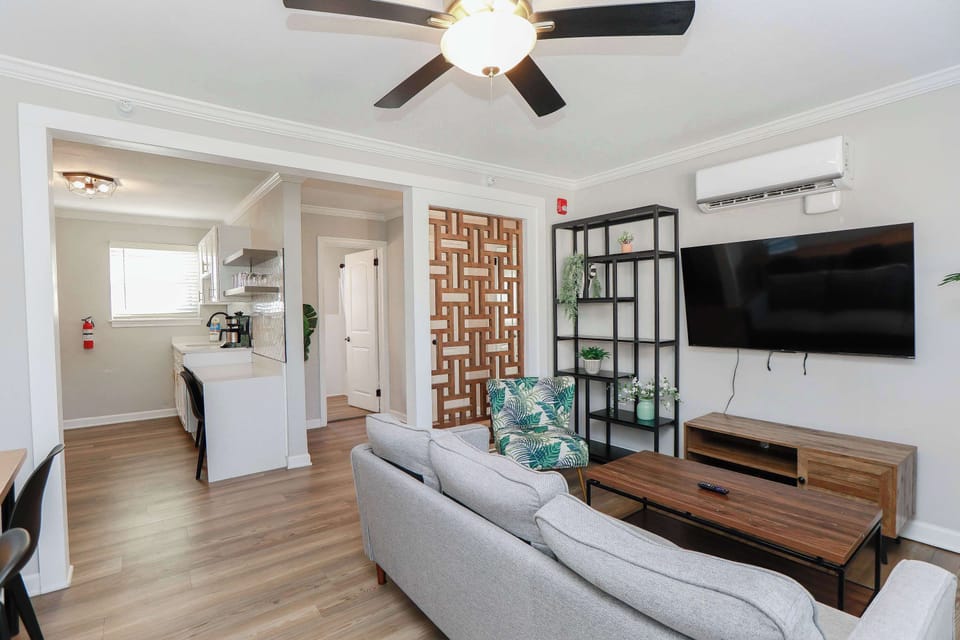 View of living room, kitchen and kitchen counter with chairs.