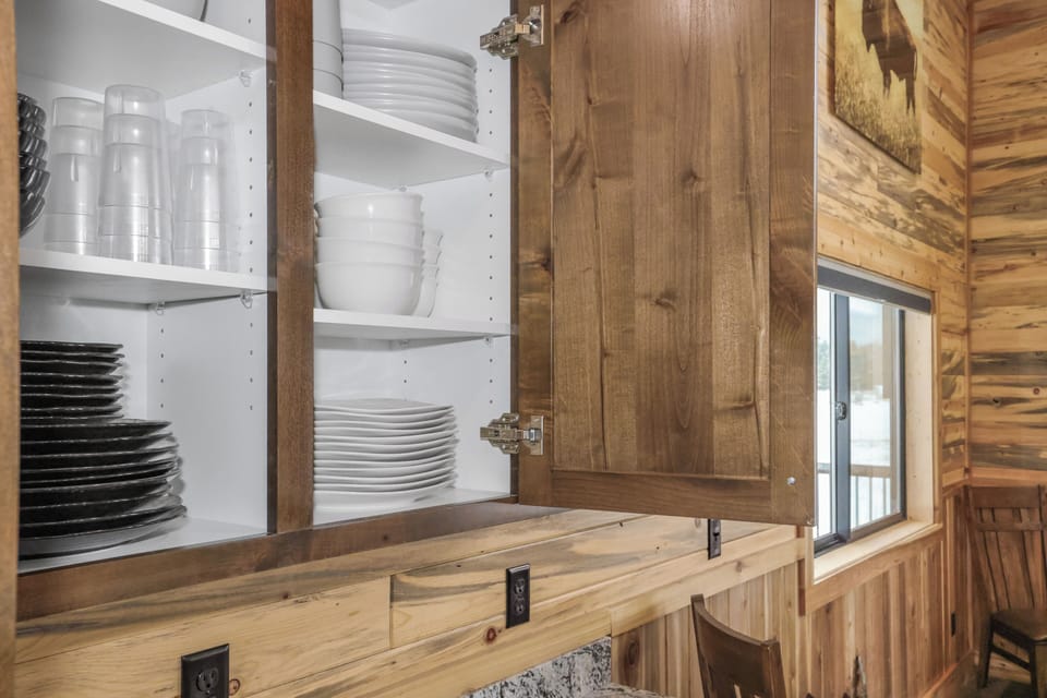 Well-stocked kitchen cabinets with dishes and glassware for group meals.