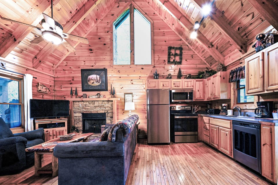 Living area featuring a fireplace, modern kitchen, and natural light from soaring A-frame windows.