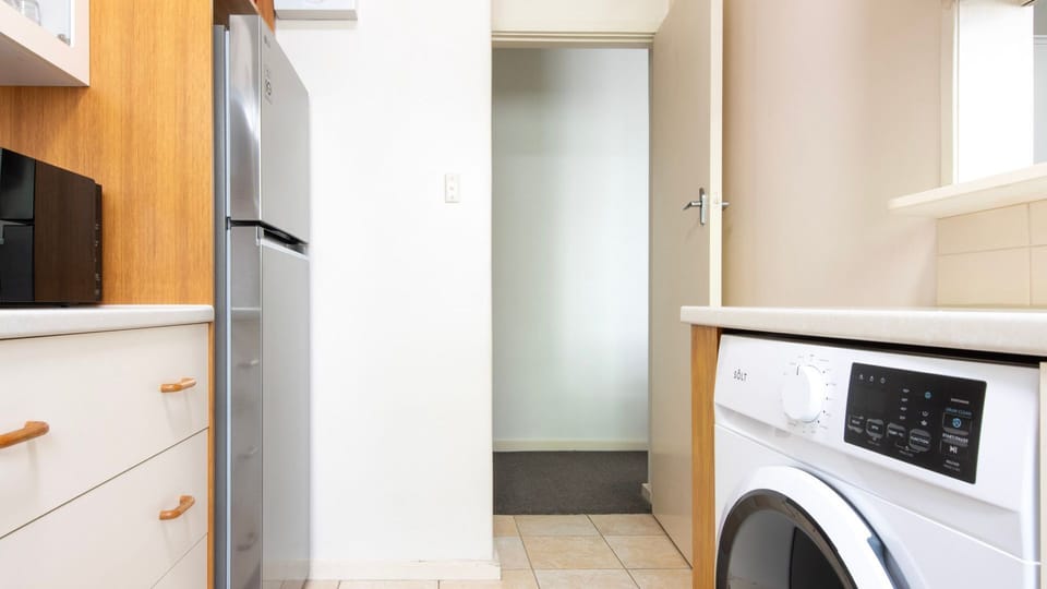 Smart utility and kitchen area with full-size fridge, laundry setup, and extra storage for daily comfort.