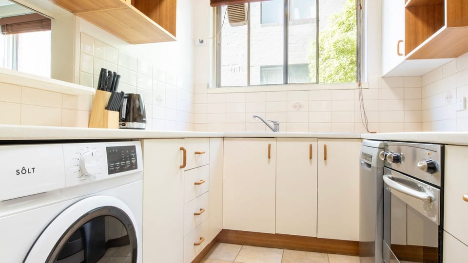 Functional kitchen corner with washer, modern appliances, and practical storage designed for convenient living.