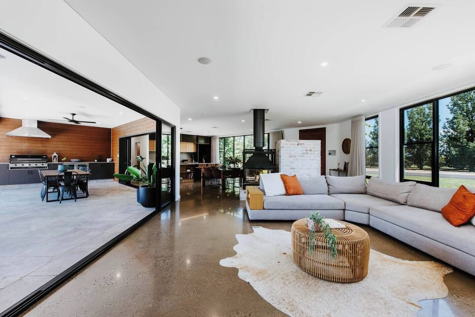 The open-plan living area flows seamlessly to the outdoor alfresco dining through large sliding doors, beautifully balancing indoors and out.
