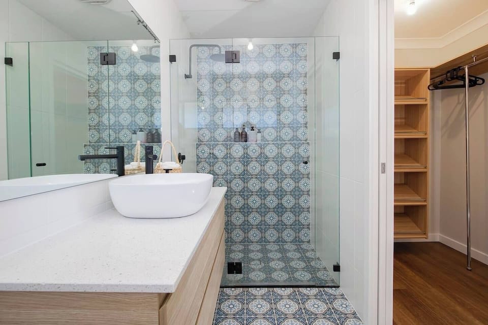 A stylish ensuite bathroom adjoins the primary bedroom and highlights a rain shower and mirrored vanity.
