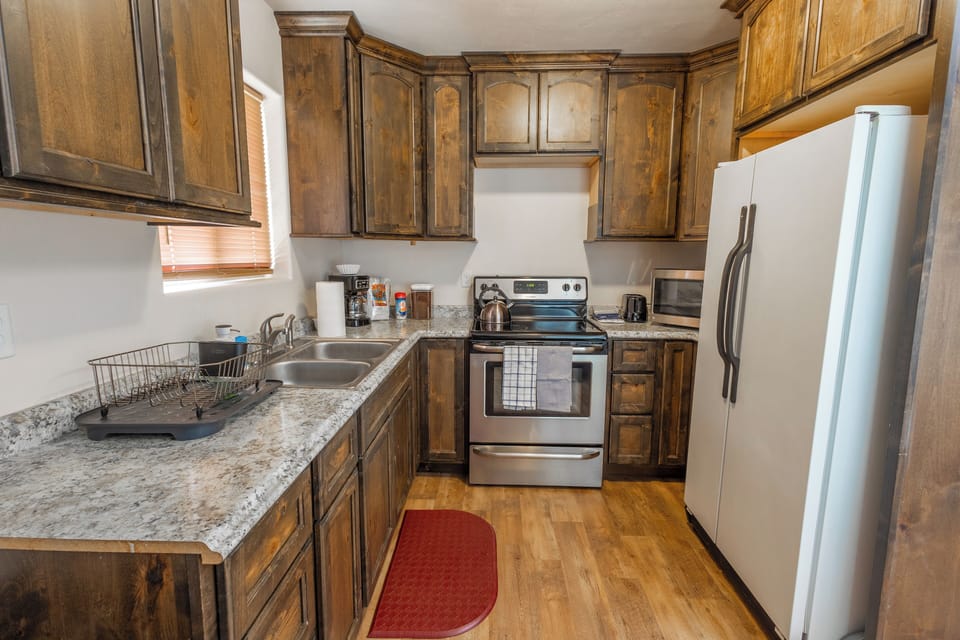 Kitchen with electric stove & oven, coffee station, microwave and cookware