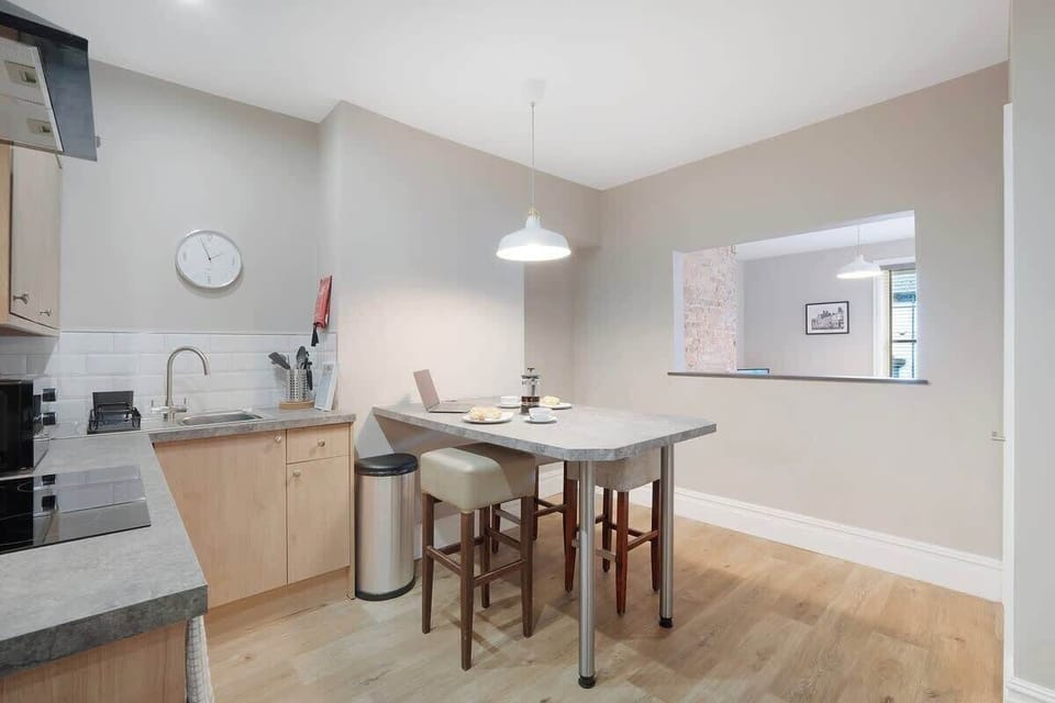 The fully equipped kitchen includes a fridge, oven, washer and dryer, and a complete cookware set. A central breakfast bar provides a comfortable space to enjoy meals, coffee, or casual conversation.
