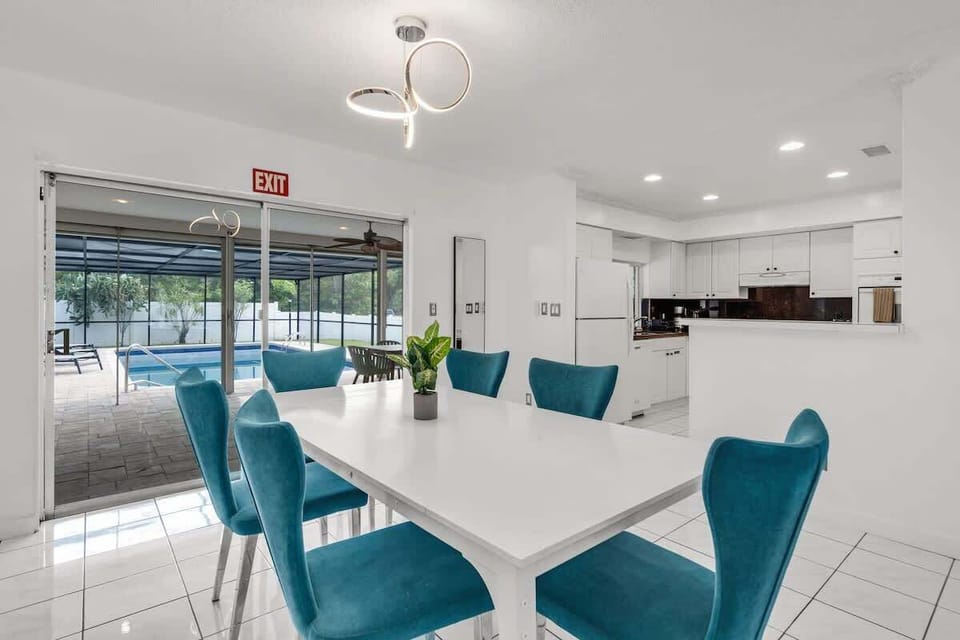 This South Florida vacation rental features a stylish dining area, modern kitchen, and seamless access to the screened pool—ideal for families, groups, or long-term stays. Book your sunny escape today!