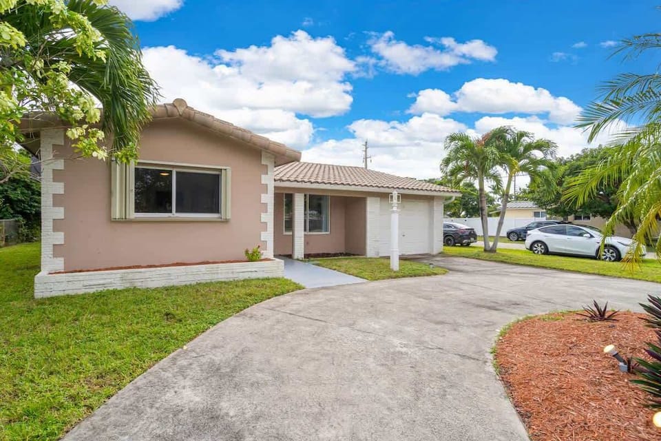 Spacious, sunny, and full of curb appeal 🌴 This South Florida vacation rental features a landscaped yard, ample parking, and a welcoming entrance—perfect for families, groups, or long-term stays. Book your relaxing escape today!