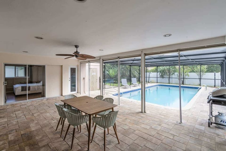 Dine, lounge, and unwind outdoors 🍽️ This vacation rental features a covered patio with ceiling fan, grill, and poolside views—perfect for families, groups, or long-term stays. Book your South Florida escape today!