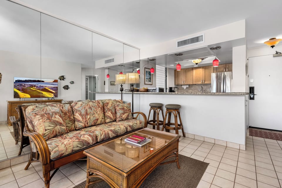 Step into your coastal retreat where the open-concept living space welcomes you with tropical charm. Settle into the comfortable seating while enjoying views to your fully equipped kitchen and breakfast bar, perfect for morning coffee or evening cocktails.